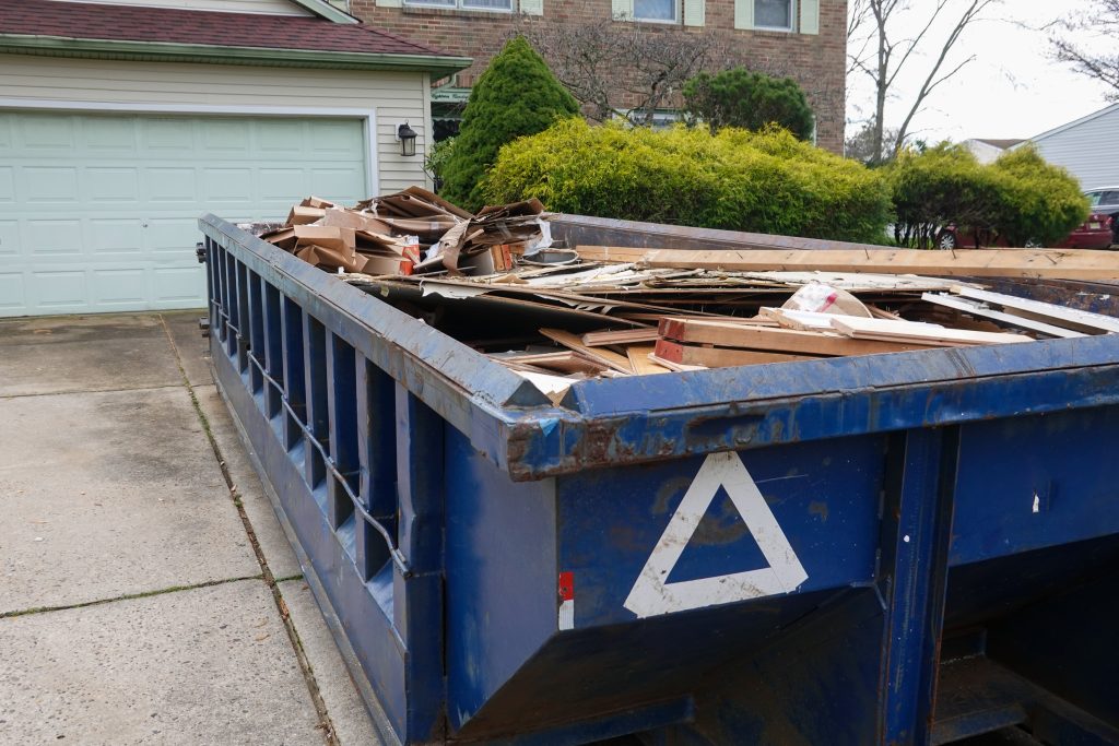dumpster filled with junk in residential driveway