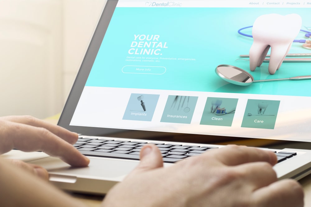 A person sitting at a desk with a laptop open to a user-friendly dental website design, showcasing easy navigation and clear calls to action.