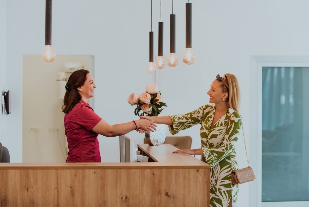 Two women shaking hands, showing a new patient gained through positive reviews.