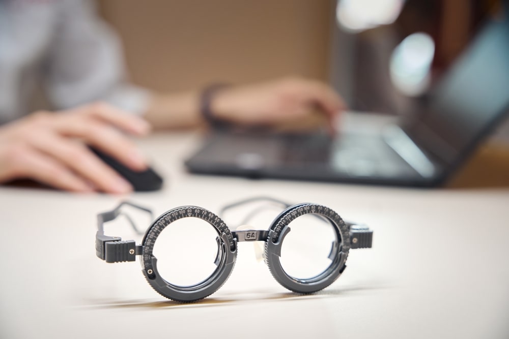 Glasses on desk while person in background is online