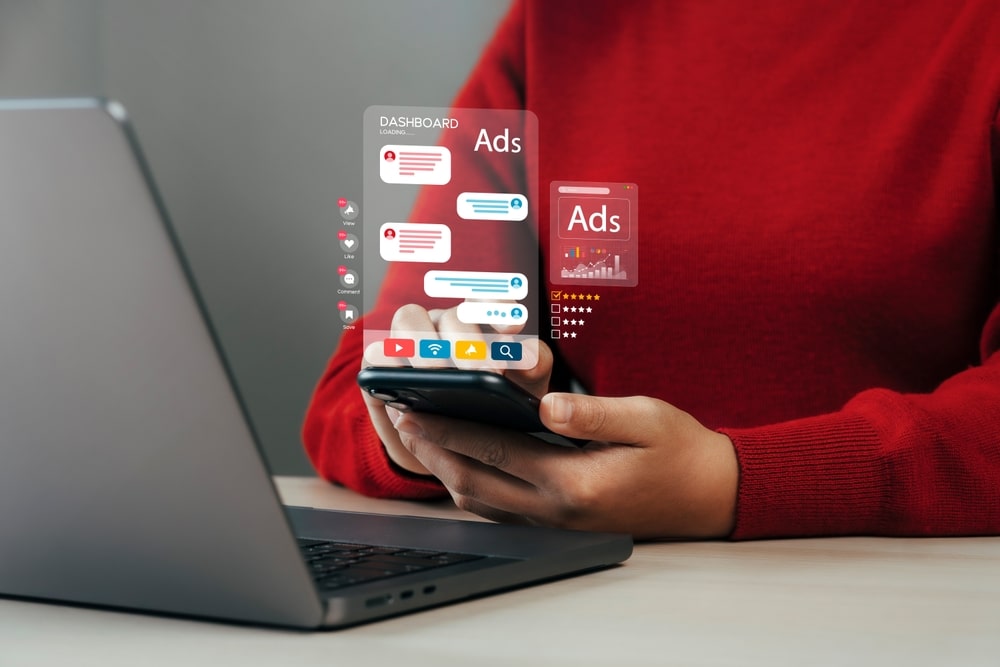 A laptop and smartphone displaying an active chat and online ads for dental services, highlighting multi-device digital marketing strategies.