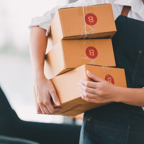 female store owner carrying three boxes