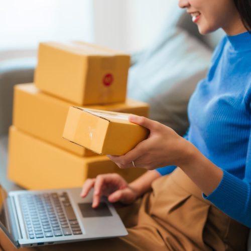 woman holding box filling out info on laptop